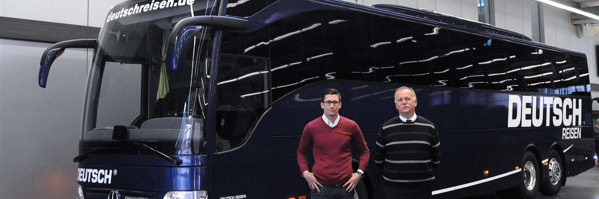 großer Blauer Bus mit 2 Personen im Vordergrund