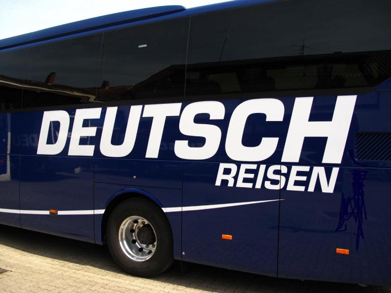 blauer Bus mit Schriftzug in Weis - Deutsch