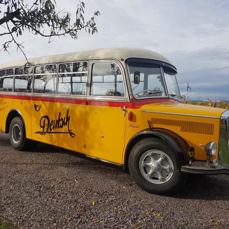 gelber Oldtimer Postbus vor blauem Himmel