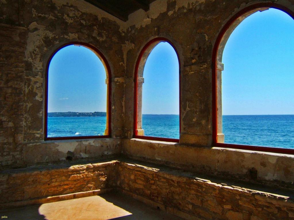 Blick durch Fenster aus Stein auf das Meer und den Himmel