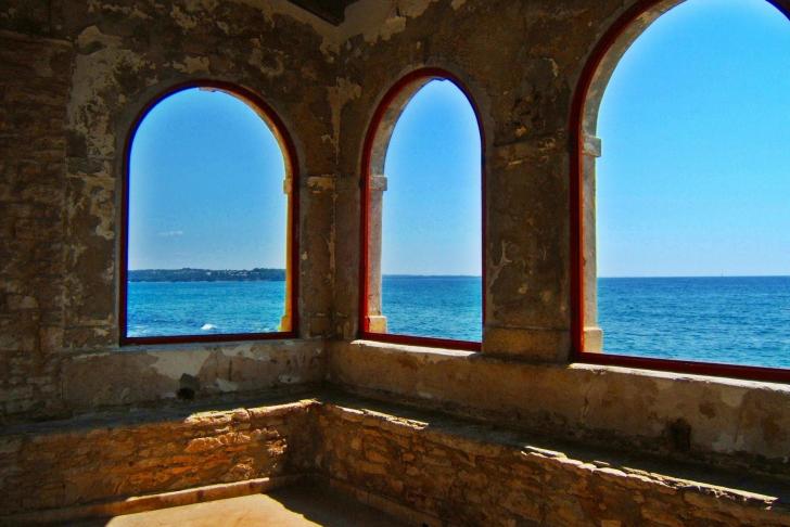 Blick durch Fenster aus Stein auf das Meer und den Himmel